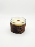 Candle in a glass jar with a leather sleeve on a white background