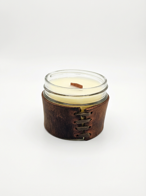 Candle in a glass jar with a leather sleeve on a white background