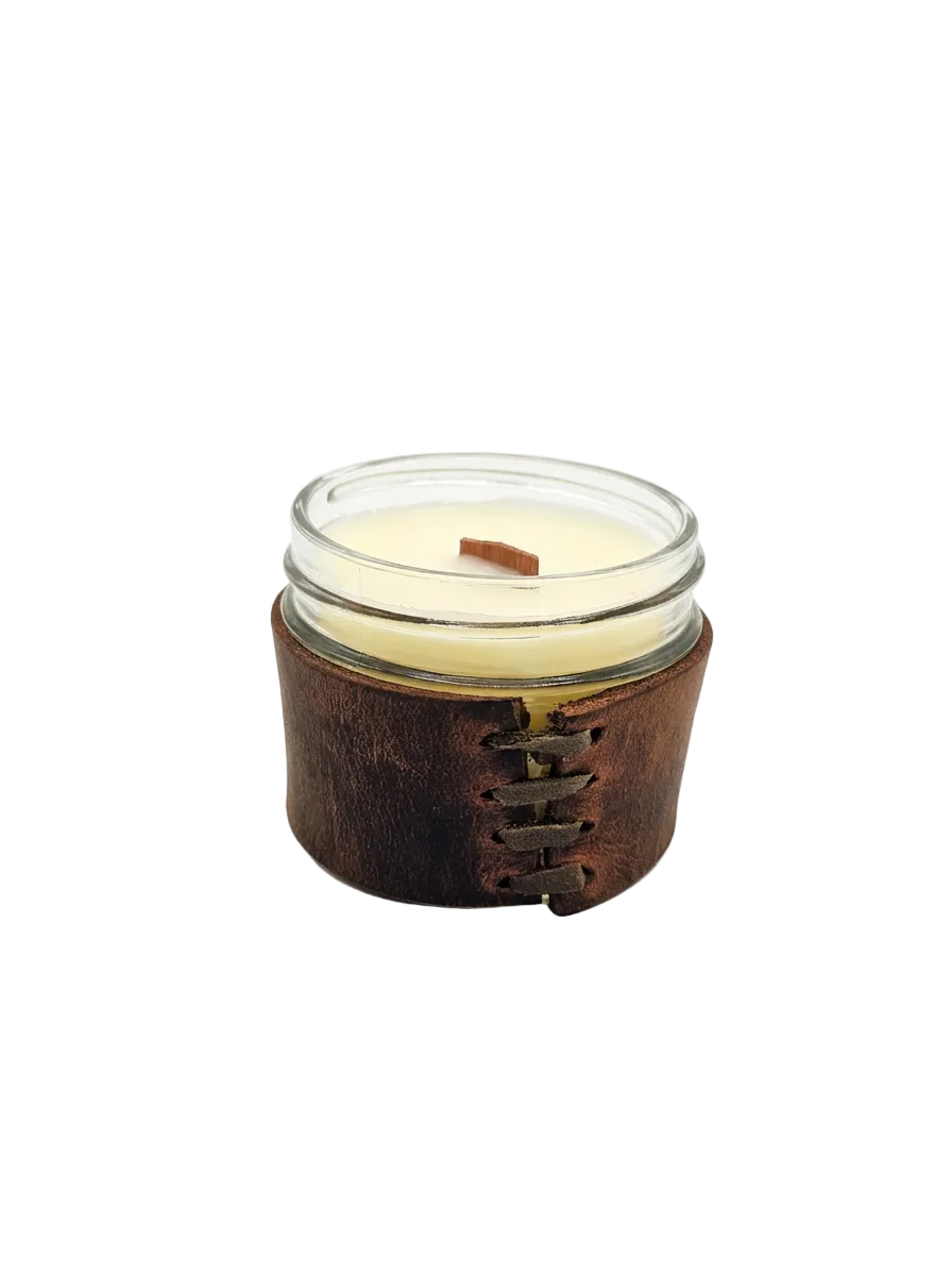 Candle in a glass jar with a leather sleeve on a white background