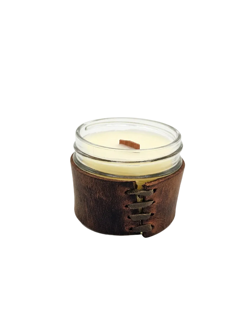 Candle in a glass jar with a leather sleeve on a white background
